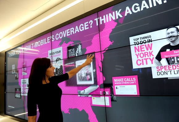 A woman points at a coverage chart in a T-Mobile store.