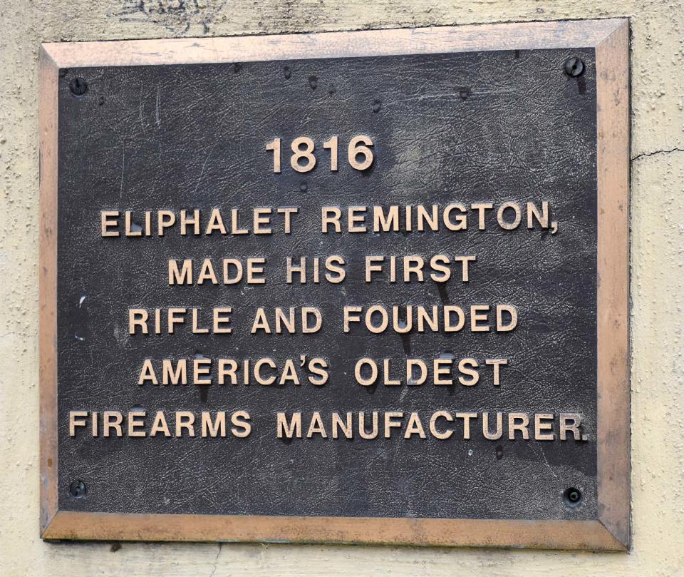 A plaque in the Ilion pedestrian mall reminds residents of the village's place in the firearms history of the United States and stands a few yards from the sire of rally Wednesday in support of almost 600 workers laid off this week by the Remington Arms Co. which has its factory across Central Avenue.