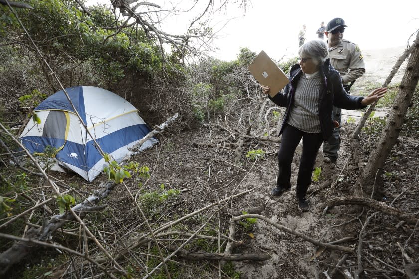 MALIBU, CA - JANUARY 22, 2020 Volunteer Kay Gabbard assisted by Los Angeles County Sheriff Deputy Santiago Cienfuegos finds a tent while looking for signs of homeless people or encampments in the Point Dume State Beach area in the City of Malibu as they participate in the 2020 Los Angeles Homeless Services Authority's annual Greater Los Angeles Homeless Count Wednesday at sunrise. The annual event coordinated by LAHSA helps to determine the number of homeless people in the region. Volunteers convened at Malibu City Hall before going to their assigned areas to conduct the count. (Al Seib / Los Angeles Times)