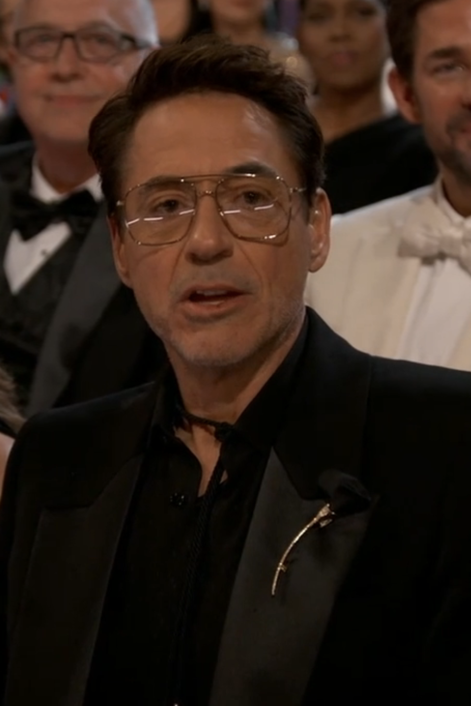 Woman in black dress and man in suit seated at an award show