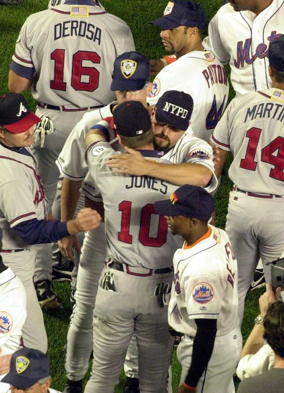 New York Mets pitcher Rick White, wearing an NYPD cap, embraces Atlanta Braves third baseman Chipper Jones before the start of the Sept. 21, 2001, game at Shea Stadium.