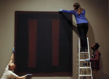 Tate staff pose with the restored Mark Rothko artwork "Black on Maroon, 1958" at the Tate Modern in London May 13, 2014. REUTERS/Luke MacGregor