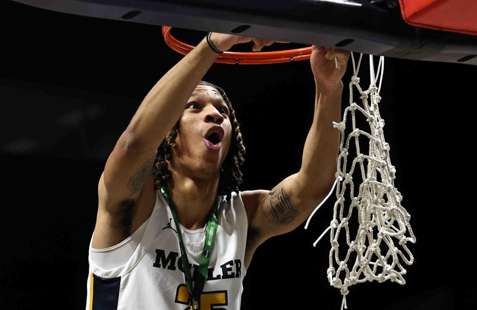 Moeller guard A.J. McBride cuts down the nets after the Crusaders'  51-34 district final win over Springboro Sunday at Cintas Center. McBride was one of three Crusaders scoring in double-digits, with 13 points.