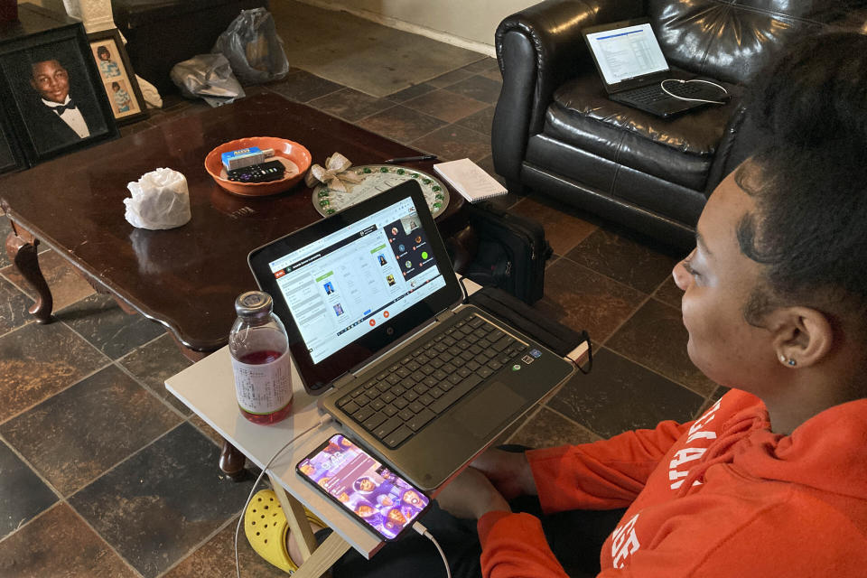 Kristen King, 17, a junior at Americus-Sumter High School, in Americus, Ga., sits on her living room couch, attending school via a Chromebook propped on a TV tray, in Americus, Ga., March 1, 2021. "It's been challenging," Kristen said. "I like hands-on help from my teachers. We can't really see our friends, like our school friends. We can't really socialize with them. We can't really do anything." (AP Photo/Jeff Amy)