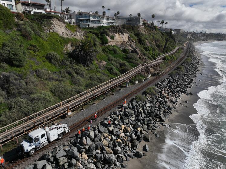 San Clemente, CA - January 25: An aerial view of Metrolink workers surveying a landslide that partially covered the train tracks and damage the Mariposa Trail Bridge, north of the San Clemente Pier in San Clemente Thursday, Jan. 25, 2024. Passenger rail service between the Laguna Niguel/Mission Viejo and Oceanside stations was suspended due to boulders and debris falling onto the tracks caused by a landslide damaging the Mariposa Trail Bridge in San Clemente, Metrolink announced, and it was uncertain today when service would resume. (Allen J. Schaben / Los Angeles Times)