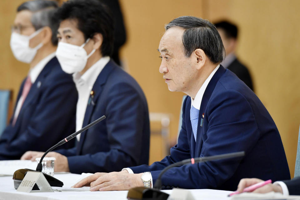 Japanese Prime Minister Yoshihide Suga, right, attends the government task force meeting for the COVID-19 measures at the prime minister's official residence in Tokyo Friday, May 28, 2021. Japan extended a coronavirus state of emergency in Tokyo and other areas for 20 more days on Friday, with infections not yet slowing to levels that would allow it to safely host the Olympics, which open in just over 50 days. (Yoshitaka Sugawara/Kyodo News via AP)