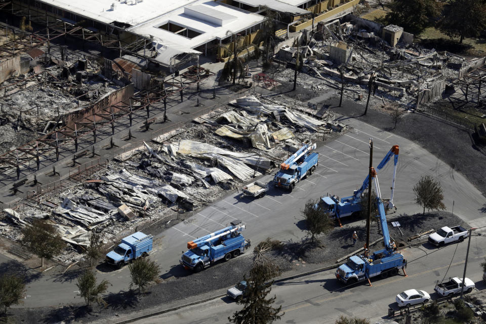 FILE - In this Oct. 14, 2017, file photo, PG&E crews work on restoring power lines in a fire ravaged neighborhood in an aerial view in the aftermath of a wildfire in Santa Rosa, Calif. PG&E says it could cut off power to a large swath of Northern California later this week to prevent its equipment from starting wildfires during hot, windy weather. The utility says power could be shut off in 30 counties in central and Northern California starting Wednesday, Oct. 9, when hot weather and strong winds are forecast, and through Thursday. (AP Photo/Marcio Jose Sanchez, File)