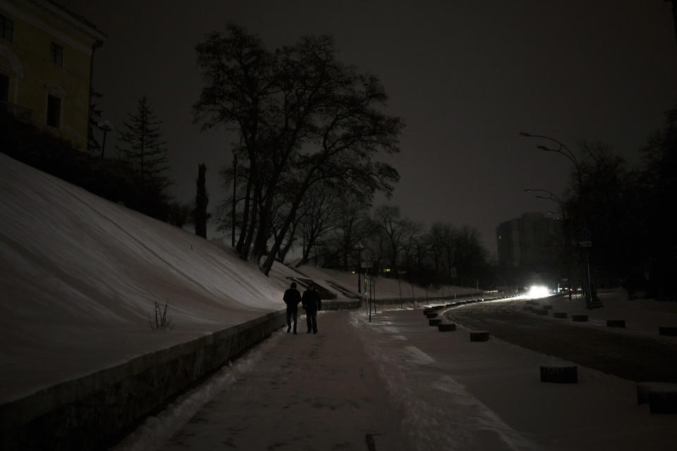 People are illuminated by a car headlight as they walk during a power outage in Kyiv, Ukraine, Thursday, Dec. 15, 2022. (AP Photo/Felipe Dana)