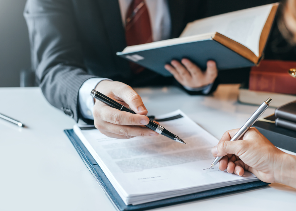 A close up of a lawyer's hands showing a client where to sign a document. 