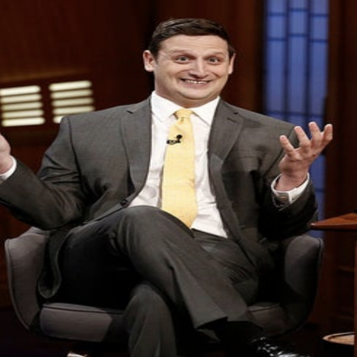 Close-up of Tim wearing a suit, sitting in a chair, and smiling