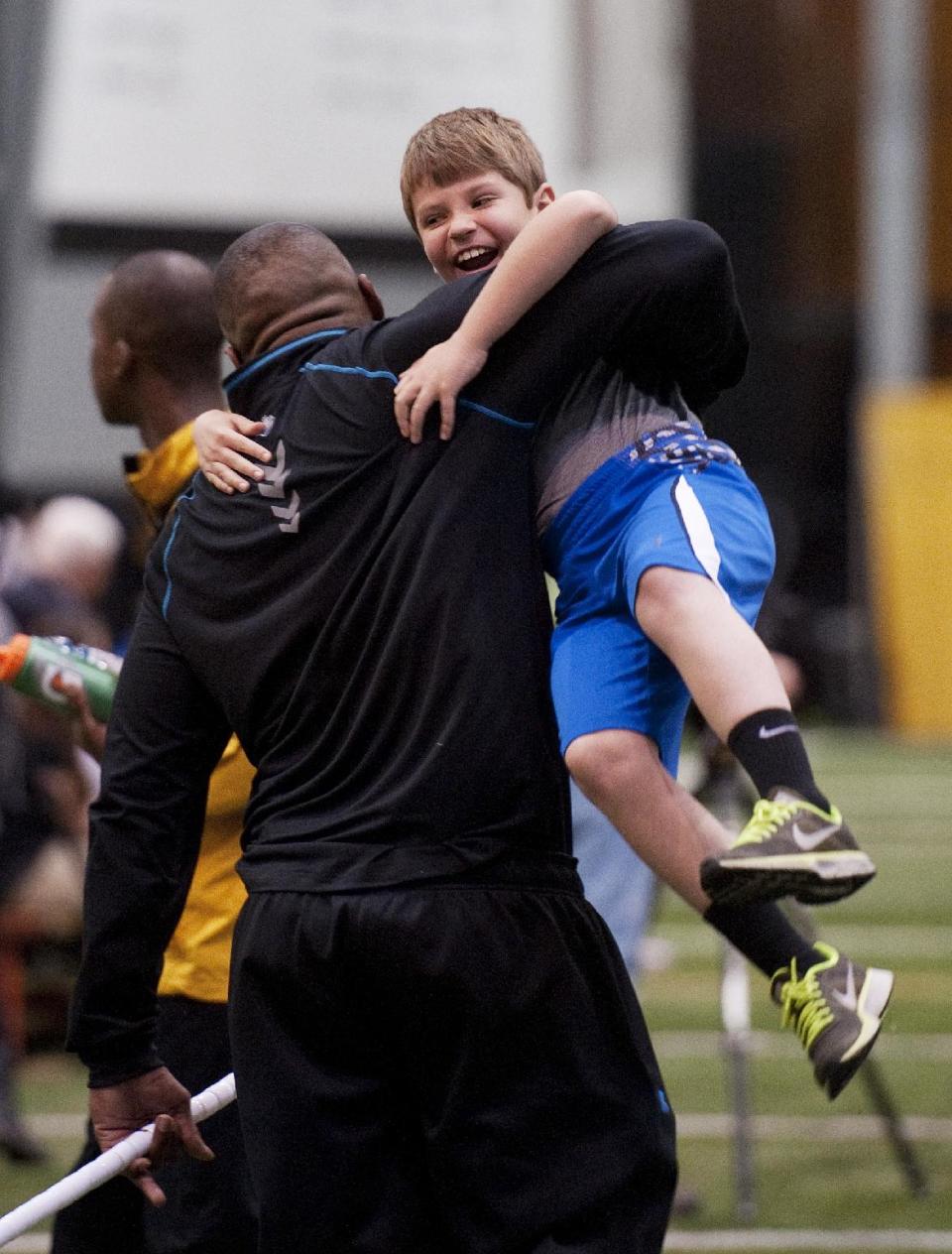 Missouri defensive lineman Michael Sam, left, picks up Andrew Hill as he greets him during pro day for NFL football representatives Thursday, March 20, 2014, in Columbia, Mo. Hill is the son of associate head coach Andy Hill. (AP Photo/L.G. Patterson)