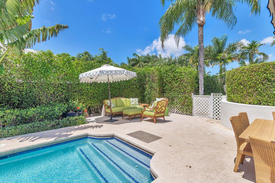 The pool area is set up for outdoor entertaining, with a lounge area and a dining table.