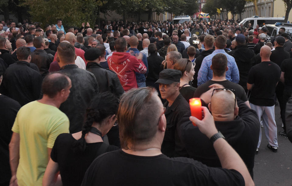 People gather in Koethen, 90 miles southwest of the German capital Berlin, Sunday, Sept. 9, 2018, after police has arrested two Afghan men on suspicion of killing a 22-year-old German man. (AP Photo/Jens Meyer)