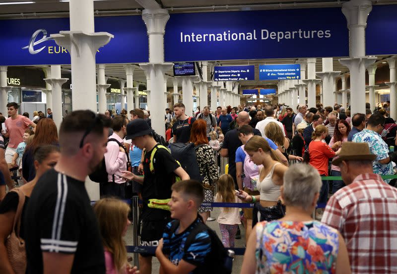 FILE PHOTO: People queue to check in for the Eurostar rail service at St Pancras International Station in London