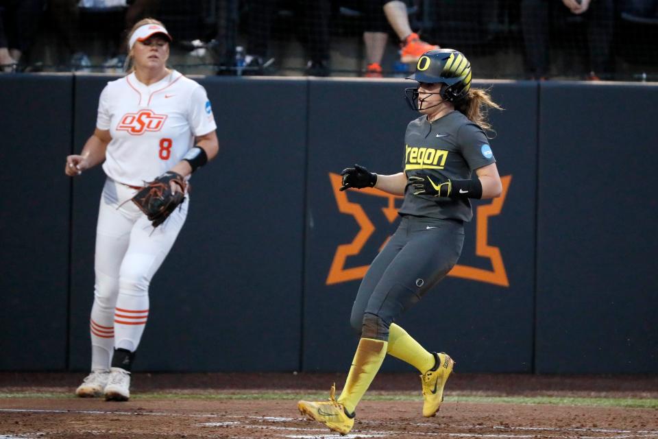 Oregon's KK Humphreys (13) scores a run beside Oklahoma State's Lexi Kilfoyl (8) inn the second inning of a game between the Oklahoma State Cowgirls (OSU) and the Oregon Ducks in the Stillwater Super Regional of the NCAA softball tournament in Stillwater, Okla., Thursday, May 25, 2023. Oklahoma State won 8-1.