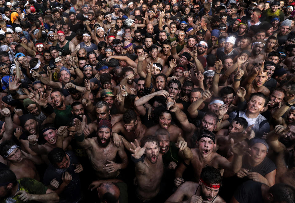 In this photo taken on Friday, Sept. 6, 2019, people painted with black grease celebrate during the traditional festivities of the Cascamorras festival in Baza, Spain. During the Cascamorras Festival, and according to an ancient tradition, participants throw black paint over each other for several hours every September 6 in the small town of Baza, in the southern province of Granada. The "Cascamorras" represents a thief who attempted to steal a religious image from a local church. People try to stop him, chasing him and throwing black paint as they run through the streets. (AP Photo/Manu Fernandez)