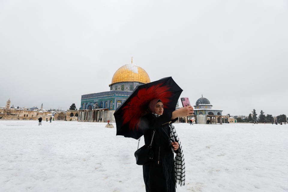 <p>A woman takes a selfie in front of the Dome of the Rock, located in Jerusalem's Old City on the compound known to Muslims as Noble Sanctuary and to Jews as Temple Mount during a snowy morning in Jerusalem's Old City, January 27, 2022. REUTERS/Ammar Awad</p>
