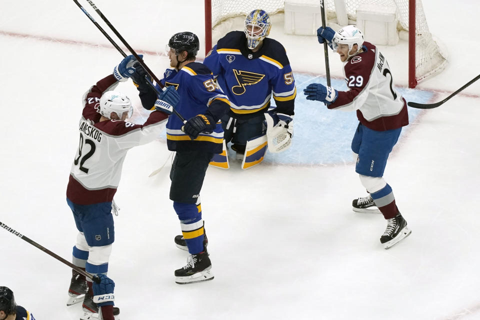 Colorado Avalanche's Gabriel Landeskog, left, is congratulated by teammate Nathan MacKinnon (29) after scoring past St. Louis Blues goaltender Jordan Binnington (50) and Colton Parayko (55) during the second period in Game 4 of an NHL hockey Stanley Cup first-round playoff series Sunday, May 23, 2021, in St. Louis. (AP Photo/Jeff Roberson)
