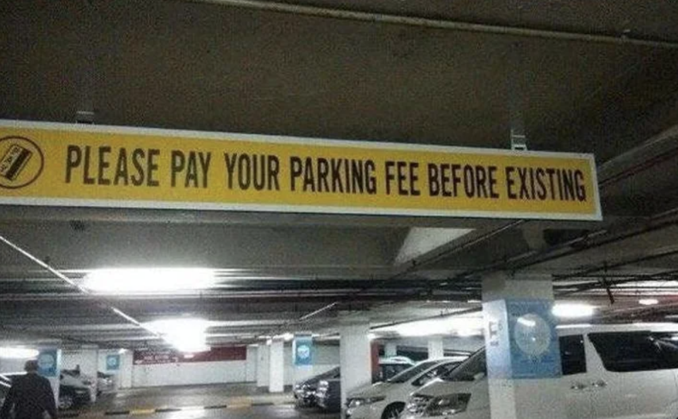 Sign in parking garage reads "Please pay your parking fee before existing," likely meaning "exiting."