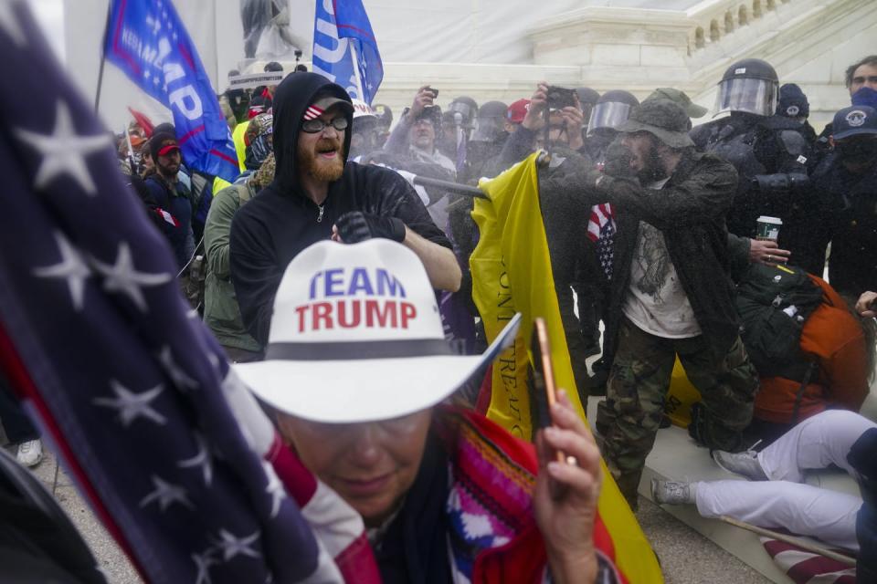 Rioters at the Capitol insurrection, including a person with a hat that says 