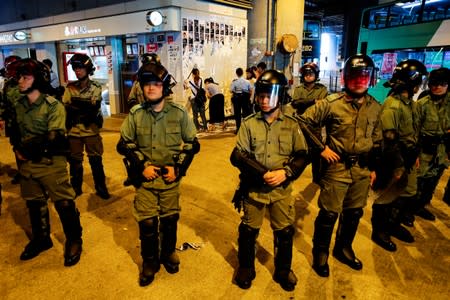 Riot police are seen in front of pro-China supporters as they pull down "Lennon Walls" of anti-government posters and memo outside Yuen Long MTR station in Hong Kong