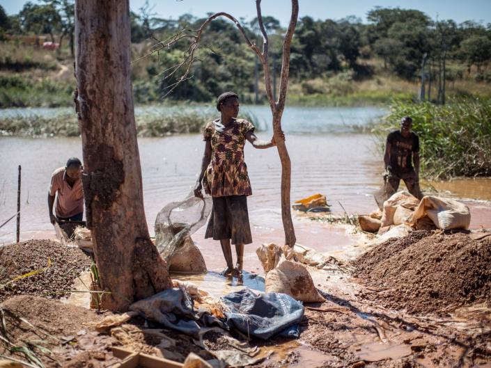 A woman and men separating cobalt from mud and rocks near a mine between Lubumbashi and Kolwezi