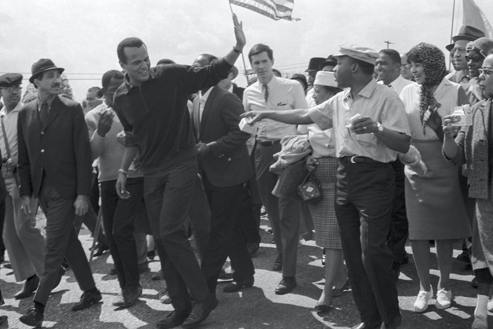 Singer Harry Belafonte waves to Dr. Martin Luther King, Jr., right, as he leaves the column of civil rights marchers in Montgomery, Ala., in 1965.