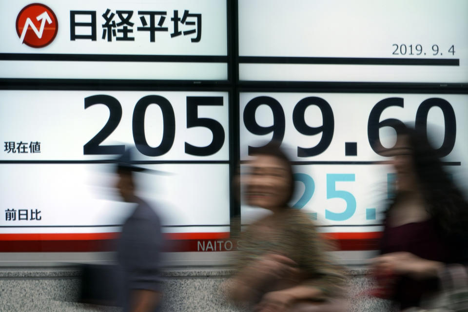 People walk past an electronic stock board showing Japan's Nikkei 225 index at a securities firm in Tokyo Wednesday, Sept. 4, 2019. Asian stock markets rose Wednesday following surprise weakness in U.S. manufacturing and wrangling in Britain over the country’s departure from the European Union. (AP Photo/Eugene Hoshiko)