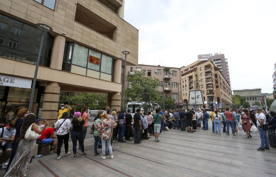 People stand in line for a vaccine shot at a mobile vaccination station in the center of in Yerevan, Armenia, Wednesday, July 14, 2021. Hundreds lined the streets of the Armenian capital to get free coronavirus shots, and some spent night on the streets to save on queueing. Under the Armenian government's directives effective since Friday, foreign nationals can only get AstraZeneca shots at five mobile vaccination points in Yerevan. (Vahram Baghdasaryan/PHOTOLURE via AP)