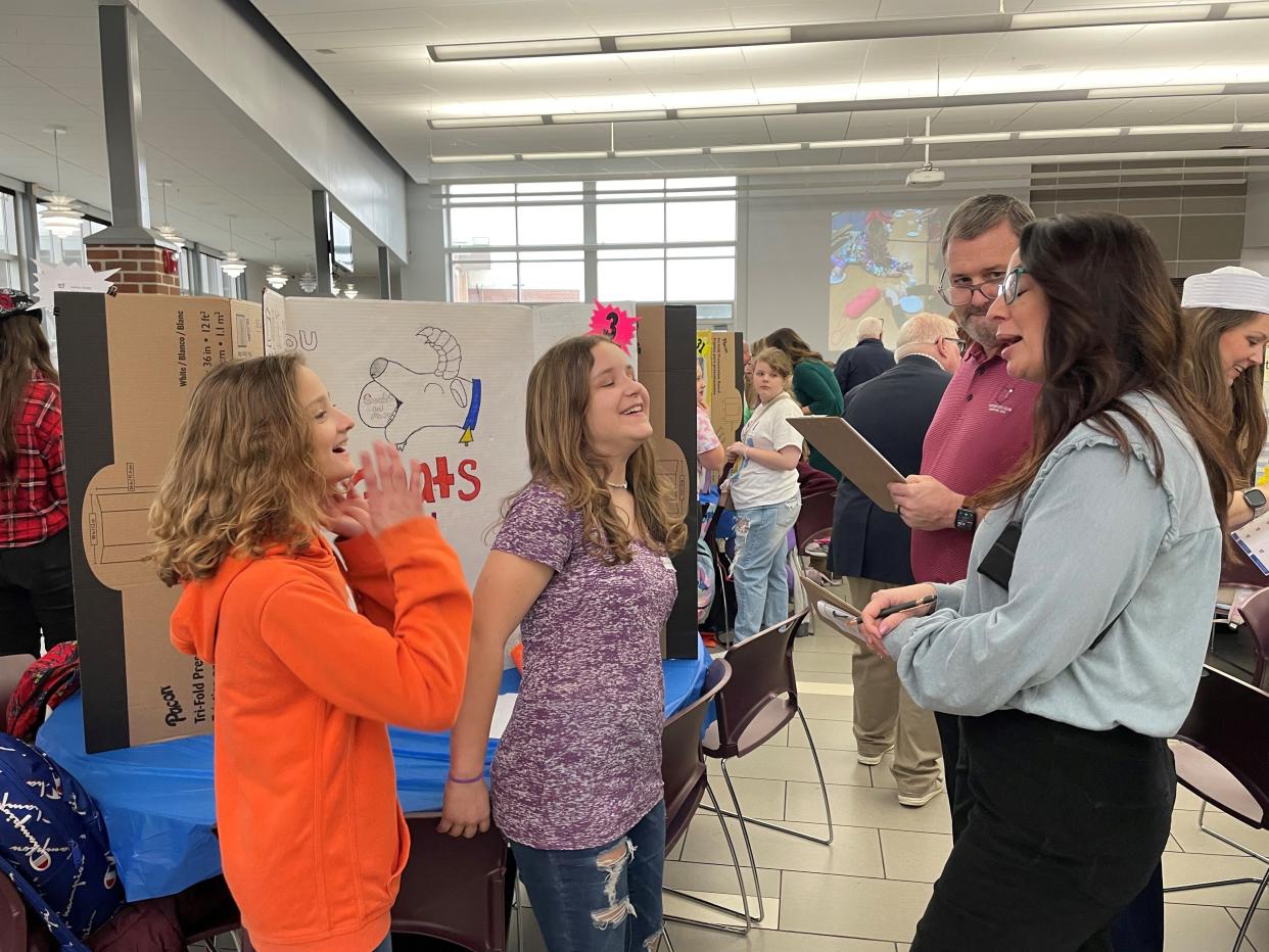 Aubrey Seasor and Myra Hartings of Newark's McGuffey Elementary share a laugh about their "Goat Breath Mints" project for the Young Entrepreneur Pitch Challenge with judges Maryann Crist and David Lewis.