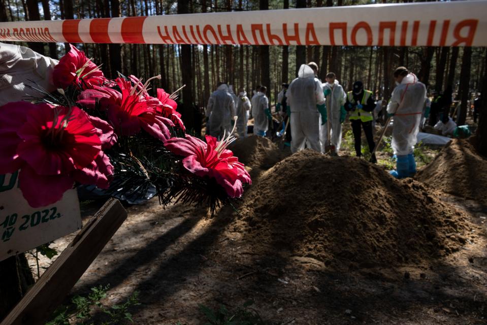 Rescue workers and forensic police exhume bodies from unidentified makeshift graves at the Pishanske cemetery in Izium, Ukraine (Getty Images)