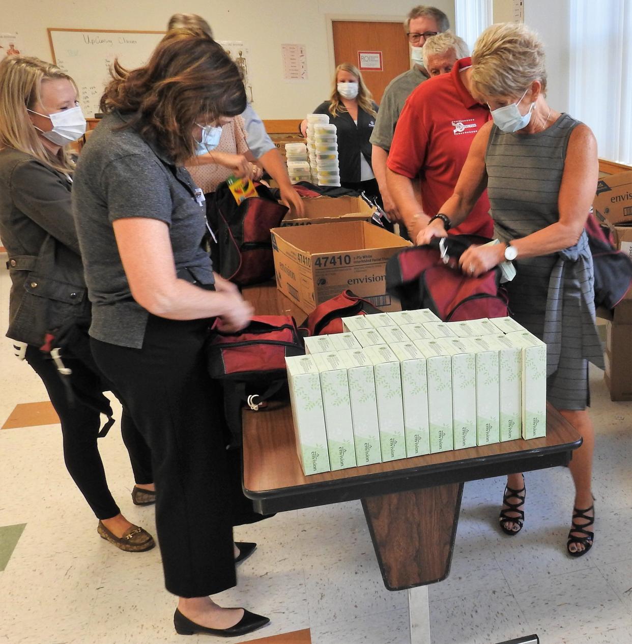 Members of the Coshocton Kiwanis Club fill backpacks, part of a campaign by Coshocton Regional Medical Center. About 3,300 area children will receive a backpack filled with items for the coming school year.