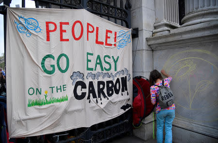 A woman draws a political slogan during the Extinction Rebellion protest at Marble Arch in London, Britain, April 22, 2019. REUTERS/Toby Melville