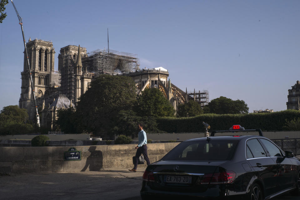 Pedestrians walk alongside the Seine River with fire-damaged sections of the Notre Dame Cathedral in view in the background, in Paris, France, Wednesday, July 24, 2019. (AP Photo/Rafael Yaghobzadeh)