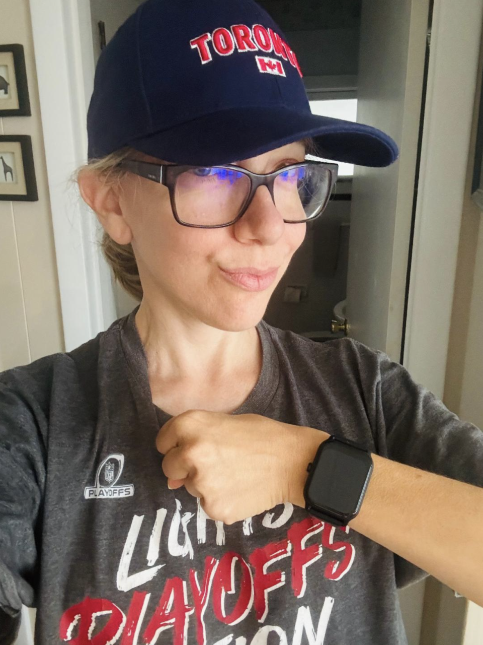 Woman wearing baseball cap and t-shirt showing black smartwatch