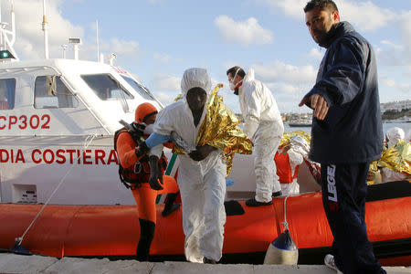 A migrant who survived a shipwreck is helped as he arrives with others at the Lampedusa harbour February 11, 2015. REUTERS/Antonio Parrinello