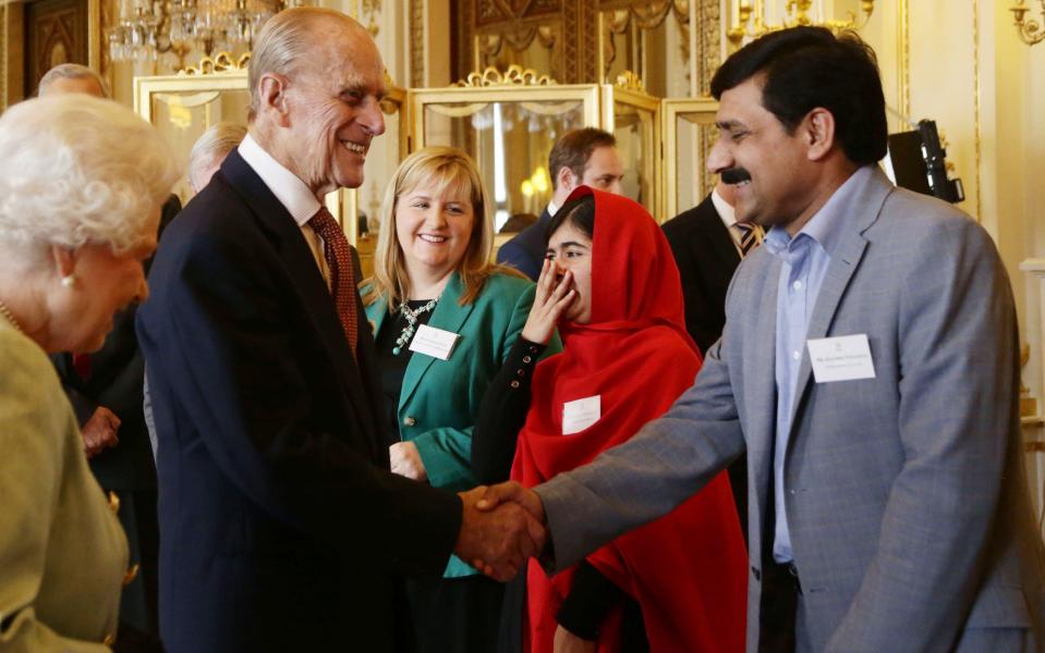 Malala Yousafzai reacts to a comment made by the Duke of Edinburgh, as he greets her father Ziauddin, during a Reception for Youth, Education and the Commonwealth at Buckingham Palace in 2013 - Credit: Yui Mok/PA