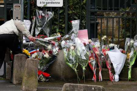 A policeman lays down flowers brought by fans in memory of late French singer and actor Johnny Hallyday in Marnes-la-Coquette near Paris, France, December 6, 2017. REUTERS/Charles Platiau