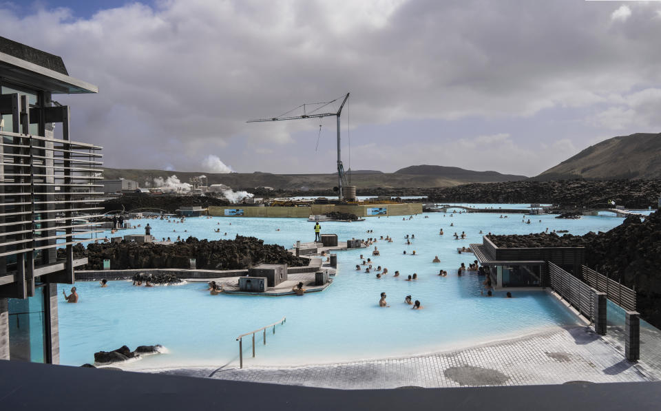 The Blue Lagoon with people bathing in it as the volcanic crater spews lava in the background in Grindavik, Iceland, Sunday, June 2, 2024. The popular Blue Lagoon geothermal spa, one of Iceland’s biggest tourist attractions in the country's southwest, was reopened Sunday after authorities said a nearby volcano had stabilized after erupting four days earlier. (AP Photo/Marco di Marco)