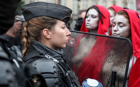 Police stand guard as 'Mariannes' from the feminist group Femen join the Paris protests - Credit: ZAKARIA ABDELKAFI/AFP/Getty Images