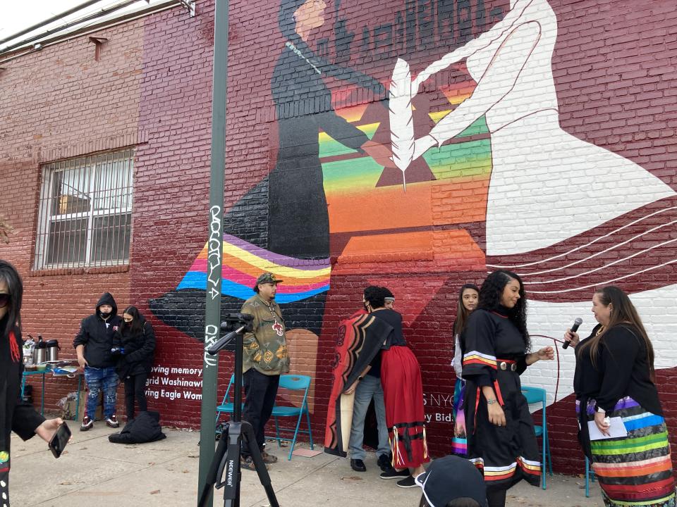 The team behind Urban Indigenous Collective gather for the unveiling of their mural dedicated to Ingrid Washinawatok El-Issa, an Indigenous woman who was murdered. Ingrid's son and husband are pictured standing at the center of the mural.