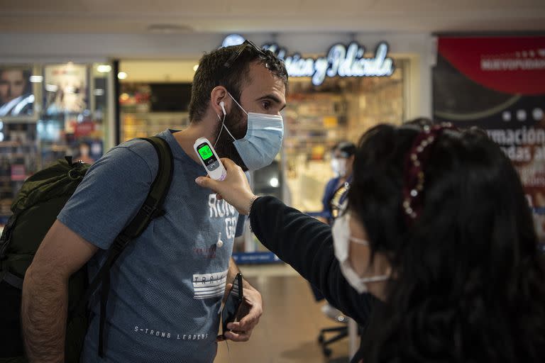 A un pasajero le toman la temperatura en el Aeropuerto Internacional Arturo Merino Benítez, hoy, en Santiago de Chile