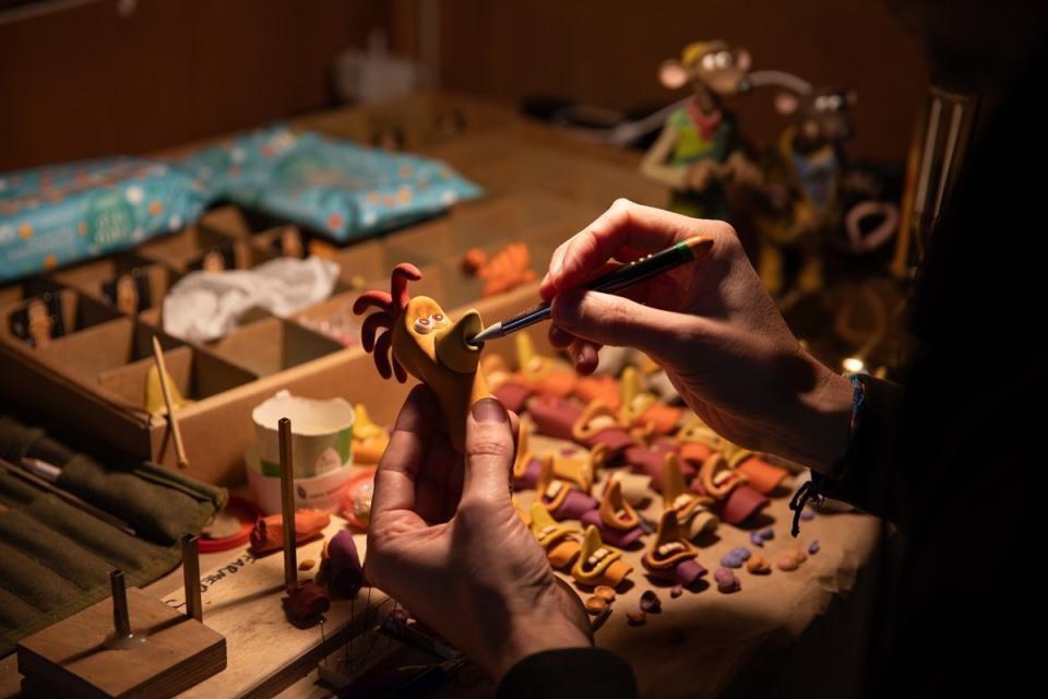 A model painter paints one of the chickens from Chicken Run: Dawn of the Nugget.