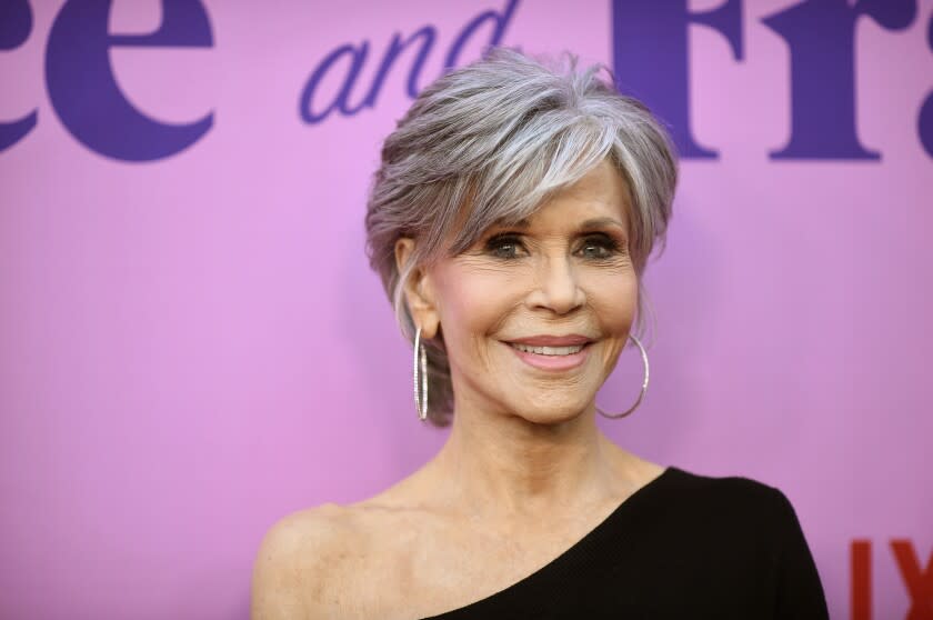 A woman with short gray hair posing in a black dress