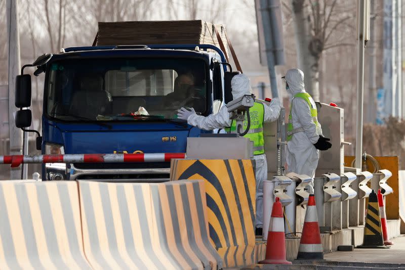 Police officers in PPE stop a car coming from Hebei province at a checkpoint on the outskirts of Beijing