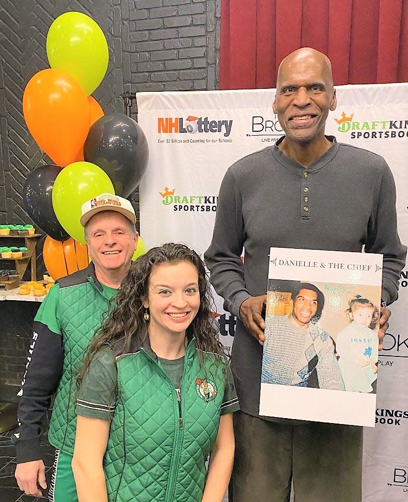 Boston Celtics legend and NBA Hall of Famer Robert Parish poses with Danielle Trial Lucini and her father, Rene, Thursday, March 30, 2023 at The Brook in Seabrook. Parish is holding a photo of himself and Danielle, then 3, at a signing in New Bedford, Massachusetts, taken in 1992.