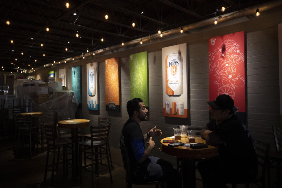 FILE - In this June 29, 2020, file photo, two men drink beers at the Mike Hess brewery and tasting room in San Diego. Authorities are closing honky tonks, bars and other drinking establishments in some parts of the U.S. to stem the surge of COVID-19 infections — a move backed by sound science about risk factors that go beyond wearing or not wearing masks. (AP Photo/Gregory Bull, File)