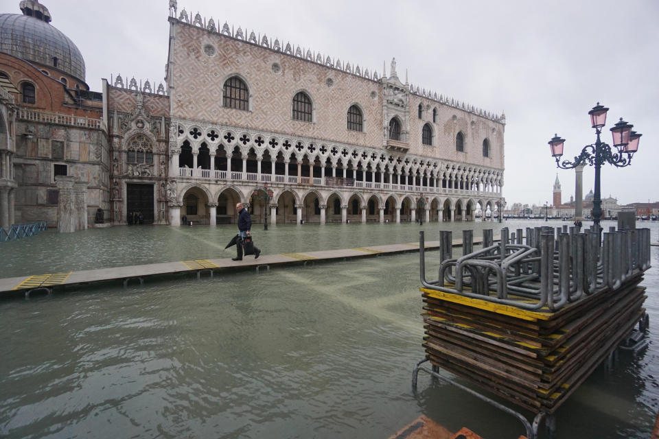 A man walks on a trestle bridge as high water floods Venice, northern Italy, Sunday, Nov. 24, 2019. The high water reached peak of 135cm (4.42ft) early Sunday. (Andrea Merola/ANSA via AP)