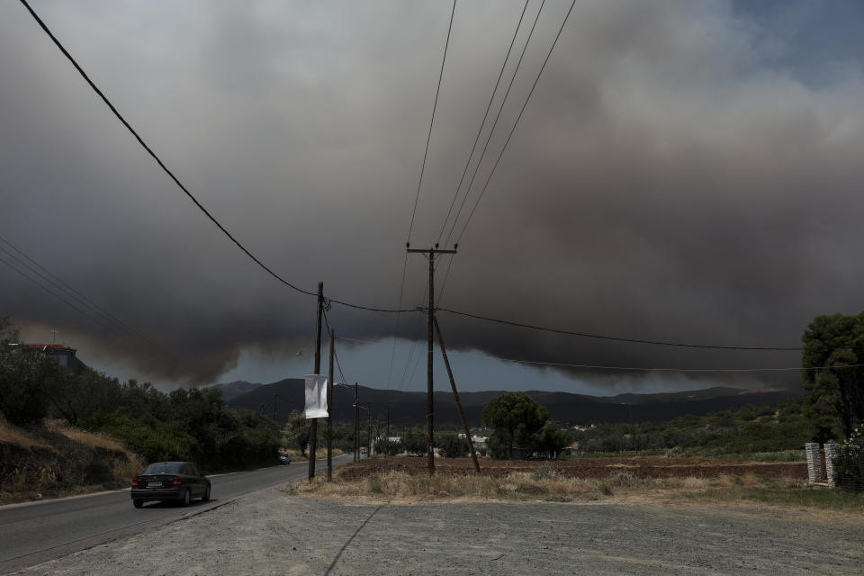 A cloud of smoke rises from a nearby forest fire at Psachna village on the island of Evia, northeast of Athens, Tuesday, Aug. 13, 2019. Dozens of firefighters backed by water-dropping aircraft are battling a wildfire on the island that has left the Greek capital blanketed in smoke. (AP Photo/Yorgos Karahalis)