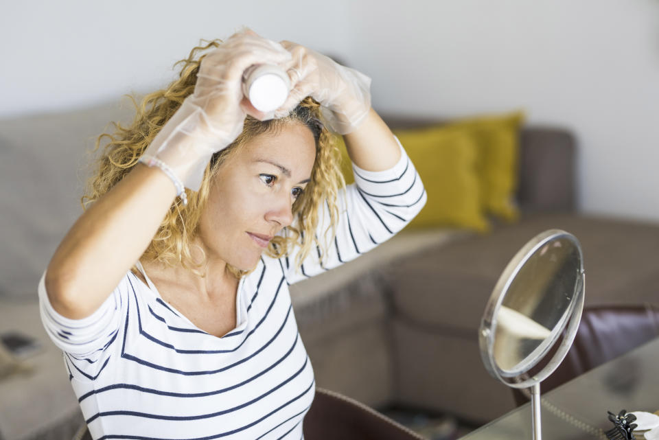 Home made hair dye at home for beauty young caucasian woman looking at the mirror - stay at home concept for coronavirus emergency worldwide pandemic contagion